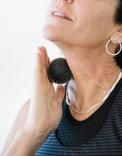 Aku Ball being applied to the neck for pain relief and relaxation